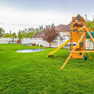 Playground Equipment And Small Pool At The Spacious Backyard Of A House