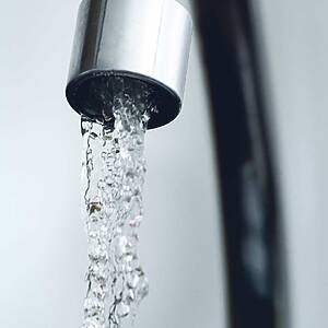 Close-up of a silver faucet with a steady stream of water flowing out.